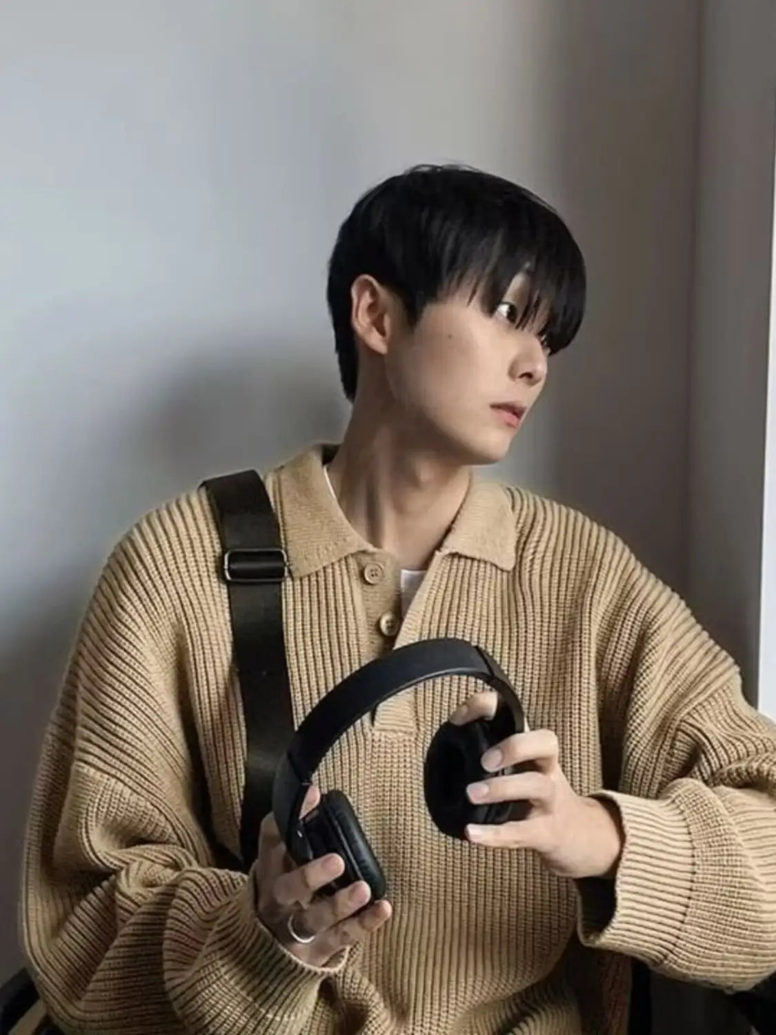 black over-ear wireless headphones with padded earcups and a sleek headband displayed alongside a men long sleeve knit polo sweater.