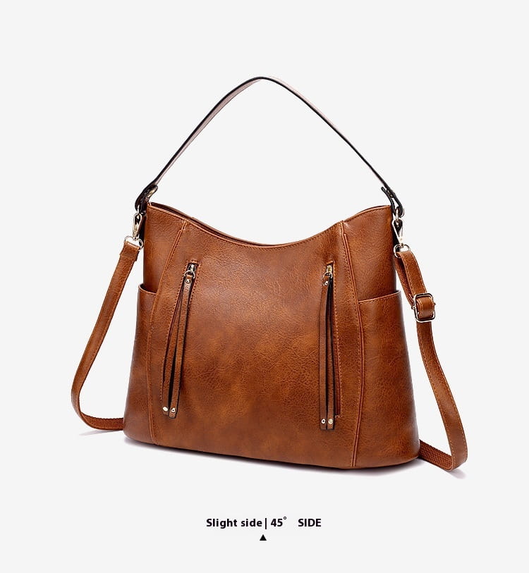 brown faux leather leather hobo bag with tassel features black shoulder and adjustable crossbody straps and front zipper pockets.