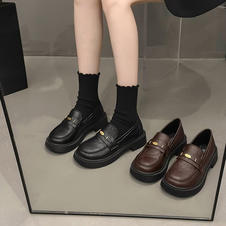 black and brown leather chunky platform loafers with gold-tone metal buckle detail visible from the front