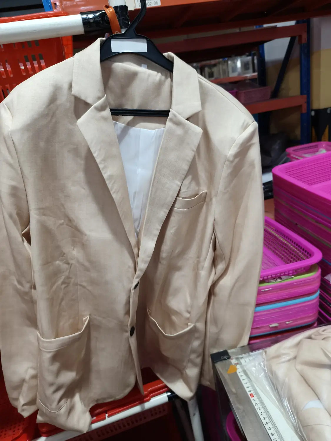 Beige blazer with a classic collar and two front pockets hanging on a black hanger from the men casual digital print suit two piece set.