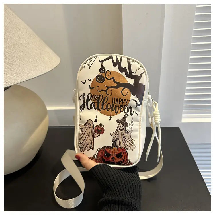 White embroidered halloween floral and pumpkin crossbody bag featuring black and orange illustrations of ghosts pumpkins and a moon.