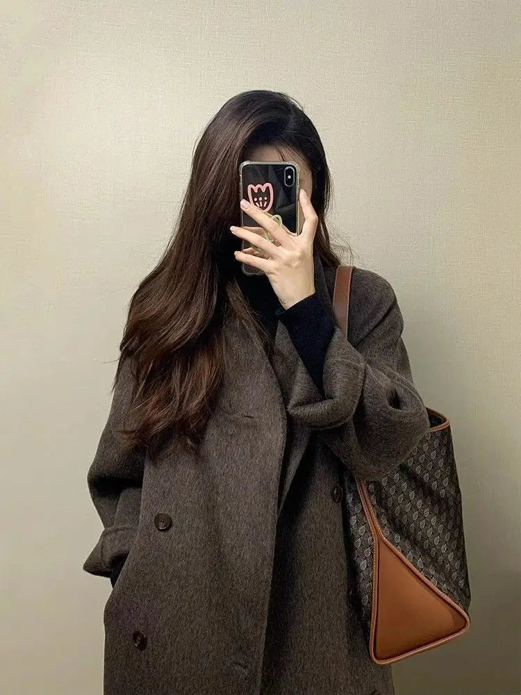 Braune Gucci-Totetasche mit dem charakteristischen Monogramm-Muster und beigem Lederbesatz, passend zum Damen-Wollmantel mit doppelreihiger Knopfleiste.