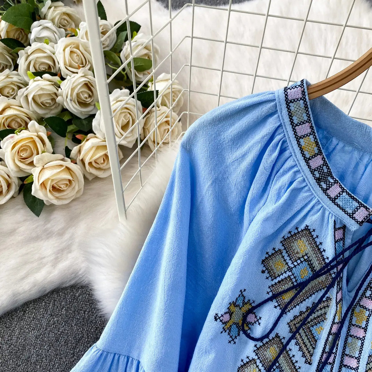 Light blue embroidered lantern sleeve tie neck blouse with intricate geometric patterns in pastel hues and dark thread accents.