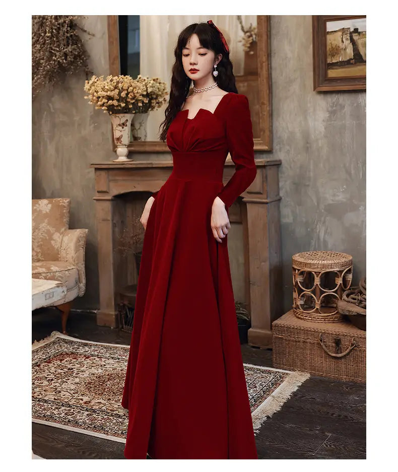 A rich burgundy velvet long sleeve A-line gown with a square neckline.