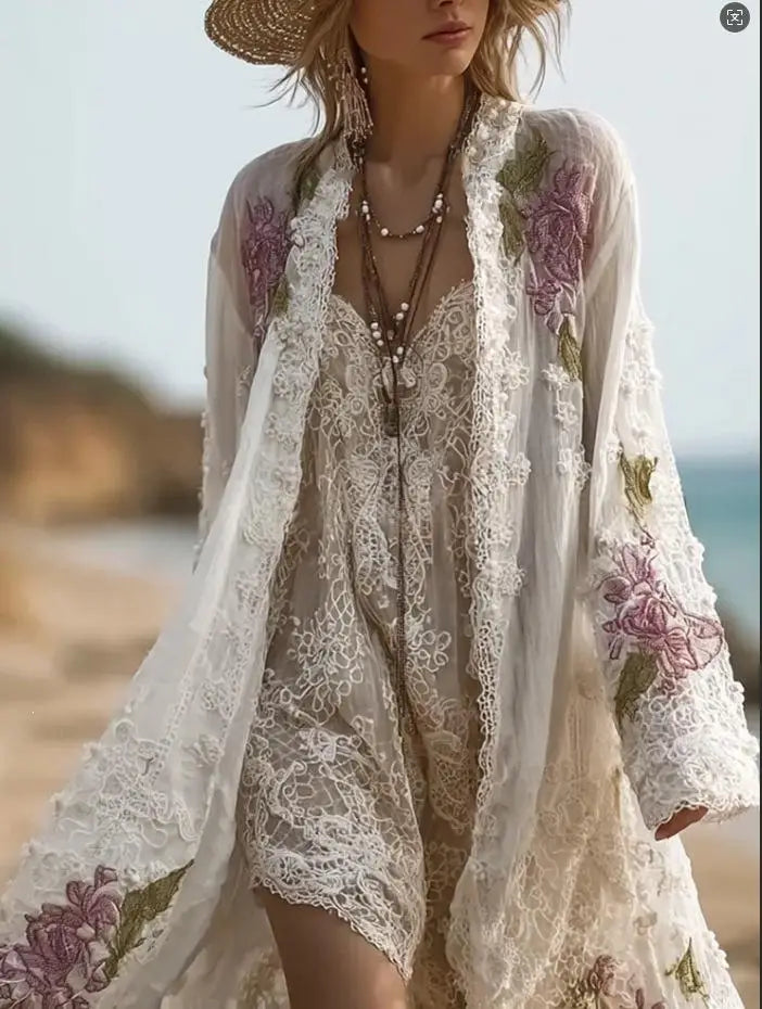 Ein fließender Kimono aus weißer Spitze mit zarter Blumenstickerei in sanften Violett- und Grüntönen, gefertigt aus einem transparenten, luftig leichten Stoff, der im Vintage-Blumenmuster-Midikleid mit langen Ärmeln enthalten ist.