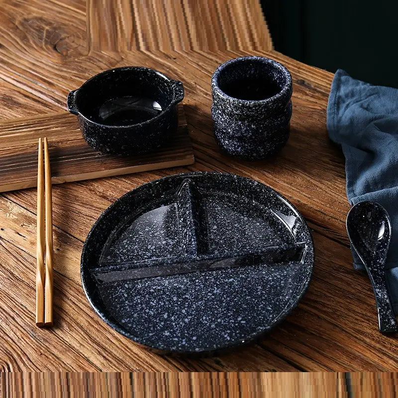 Assiette de dîner divisée en céramique noire à mouchetures, avec finition vitrifiée et une conception fonctionnelle segmentée.