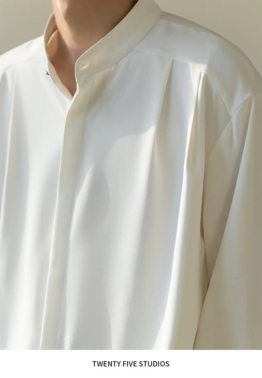 Chemise plissée pour homme blanche éclatante à col montant, présentant des manches longues, un col impeccable et des plis subtils sur l’avant.