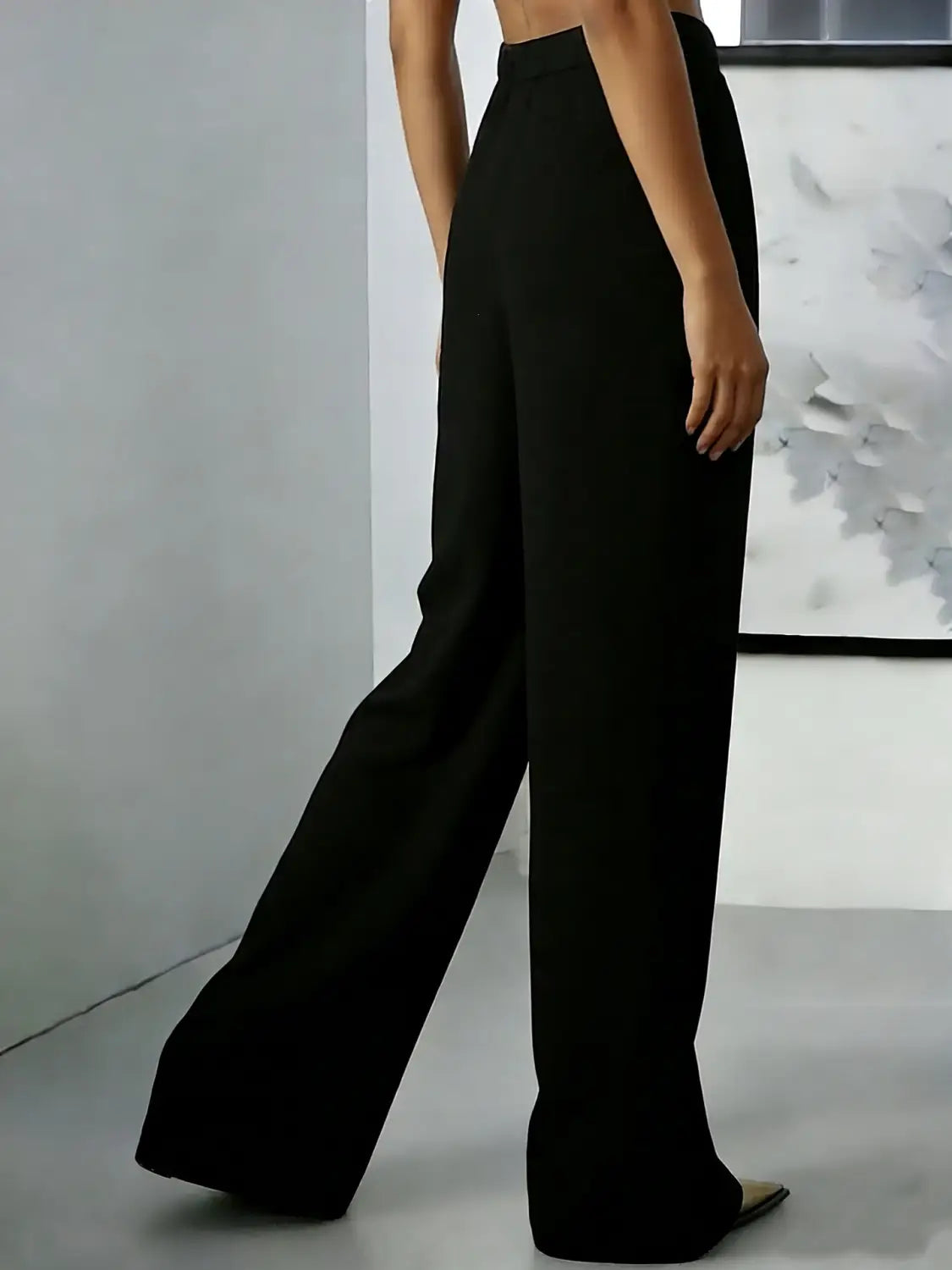 Pantalons noirs à taille haute et jambes larges, avec un design minimaliste épuré et des détails plissés, adaptés aux tenues formelles ou décontractées.