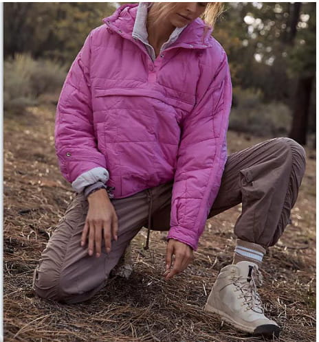 Eine leuchtend pinkfarbene gesteppte Damen-Steppjacke mit Kapuze mit grauer Innenauskleidung.