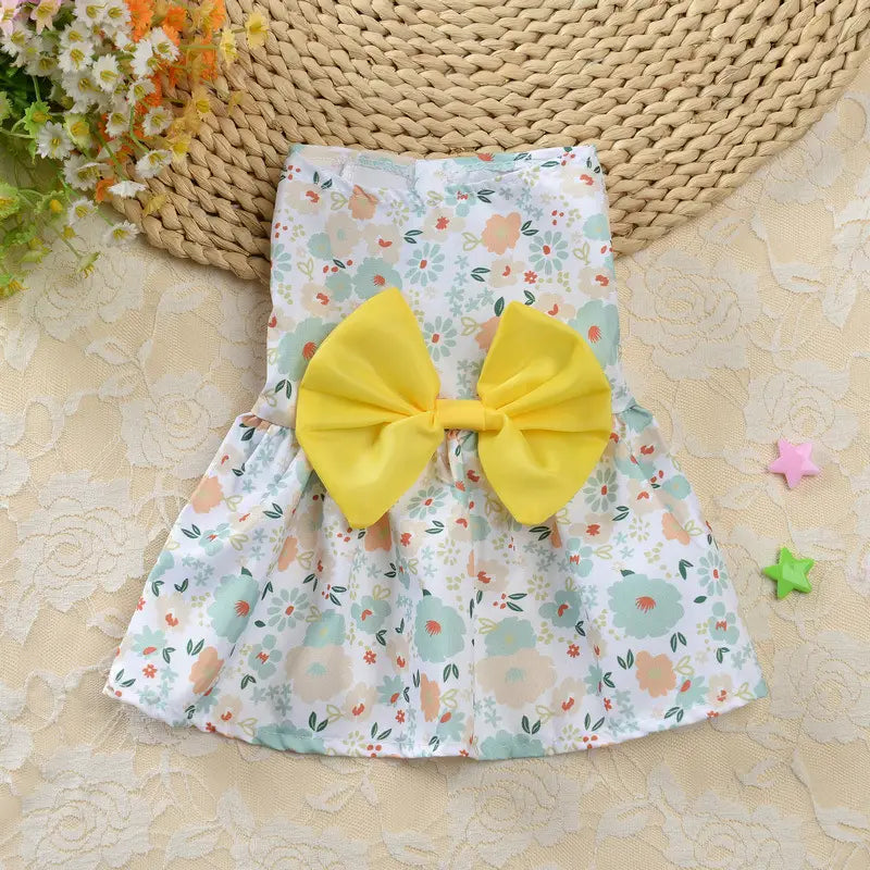 A charming white floral dog princess dress with a vibrant yellow bow at the front designed as strawberry daisy pet apparel.