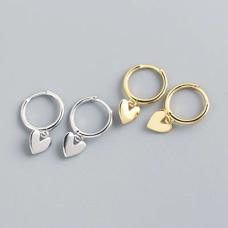 Minimalistische herzförmige Creolen aus Silber und Gold mit polierten Metalloberflächen und Anhänger-Design.