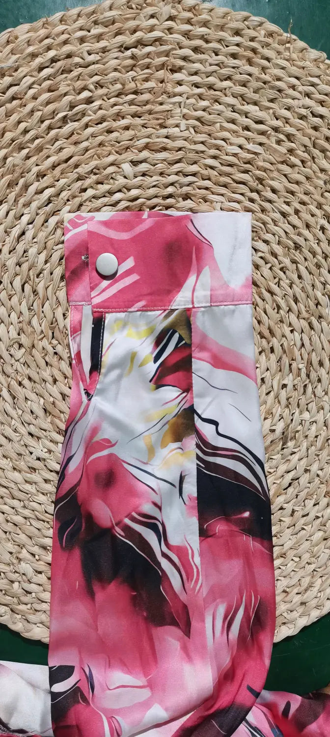 A vibrant pink white and black floral patterned satin sleeve with a silver button at the top featured on a women’s marble print satin long sleeve button blouse.