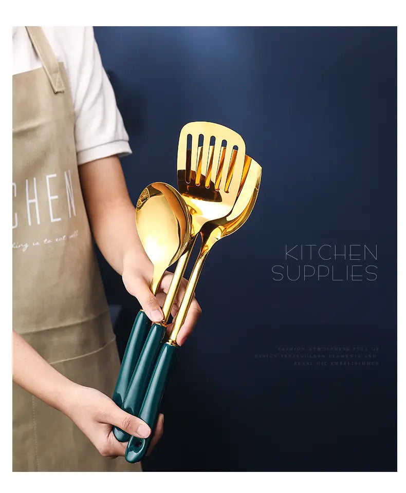 goldener Satz aus Edelstahl-Küchenutensilien mit schlanken, reflektierenden Metallköpfen und matt-dunkelgrünen Griffen zum Kochen und Servieren