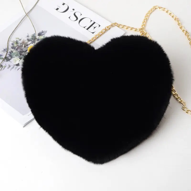 Black heart shaped crossbody bag made of plush faux fur with a gold chain strap.