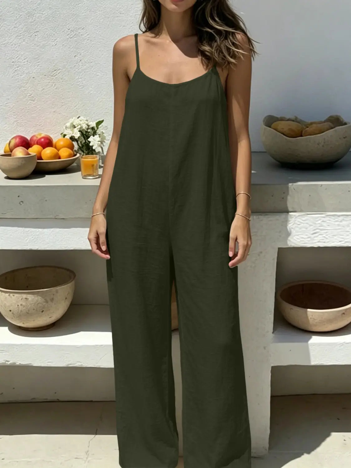 olive green linen sleeveless wide-leg jumpsuit with thin spaghetti straps and a backless design displaying the rear side of the garment