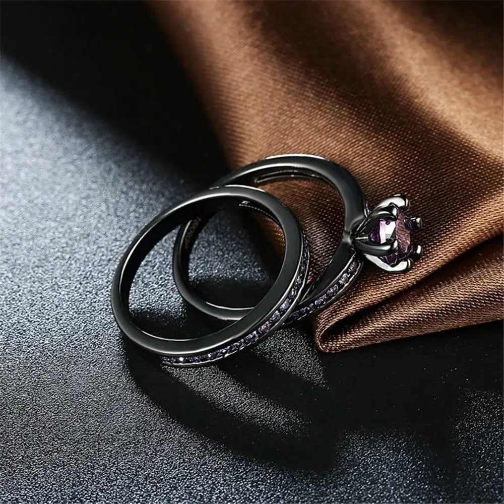 Black tungsten and purple gemstone wedding band set featuring a black engagement ring with a purple gemstone and pave-set diamonds paired with a matching black band.