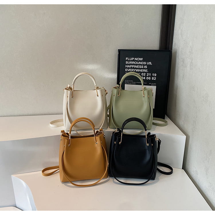 Minimalist leather bucket bags with detachable straps in cream sage green camel and black leather featuring top handles.