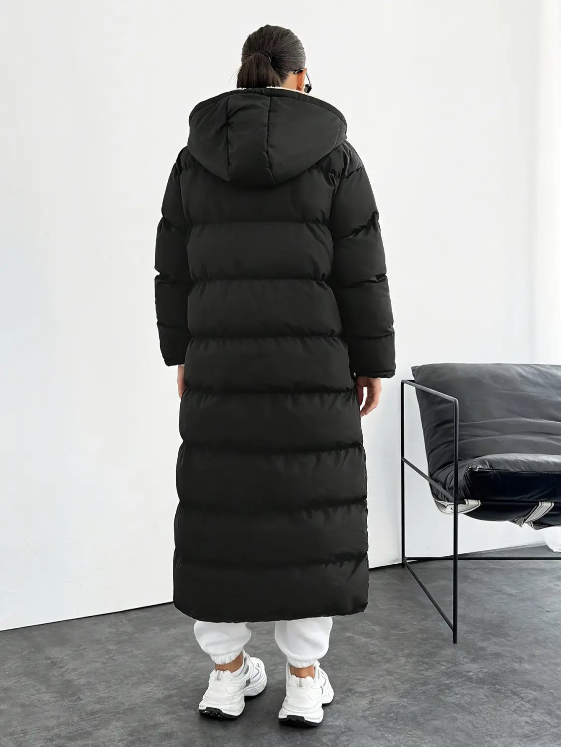 Black hooded quilted long puffer coat featuring horizontal stitching and a warm insulated design.