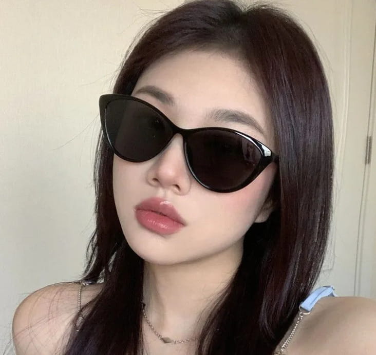 Lunettes de soleil œil-de-chat de couleur noire avec des verres foncés et un cadre élégant et brillant, offrant une protection UV380 légère, pour un usage mode.