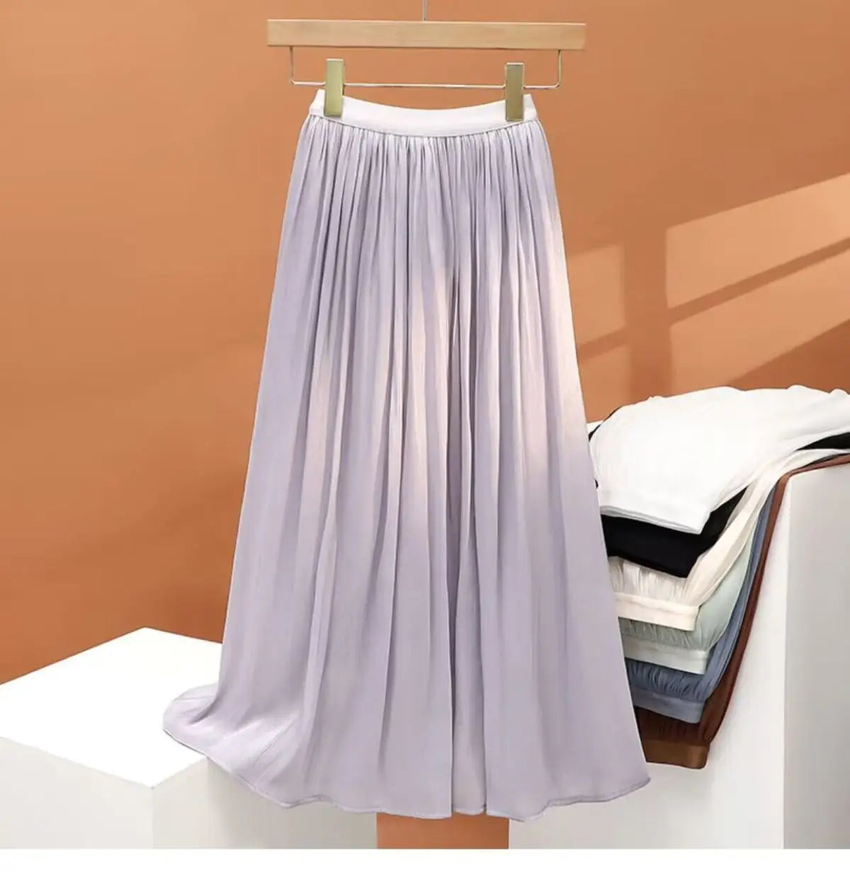 Ein fließender lavendelfarbener irrisierender Chiffon-Faltenrock im Midi-Format mit weißem Bund aus leichtem Gewebe.