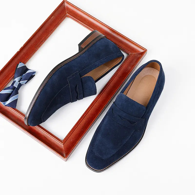 Men’s navy blue suede loafers with classic penny loafer design and contrasting black soles for casual leather shoes.
