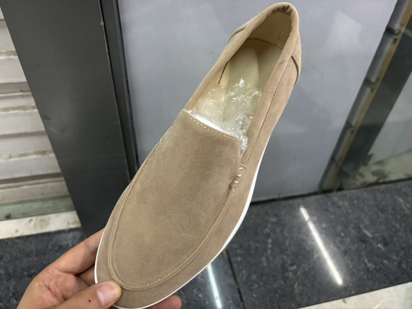 Mocasines de ante color beige para hombre con suela de goma blanca, diseñados como calzado tipo slip-on.