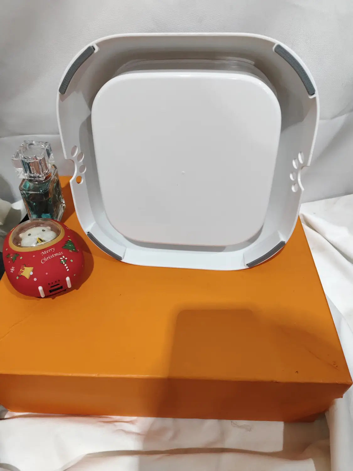 White rectangular robot vacuum cleaner with gray accents and paw print cutouts designed for pet use shown alongside an anti-splash pet floating water bowl with 1.5l capacity.