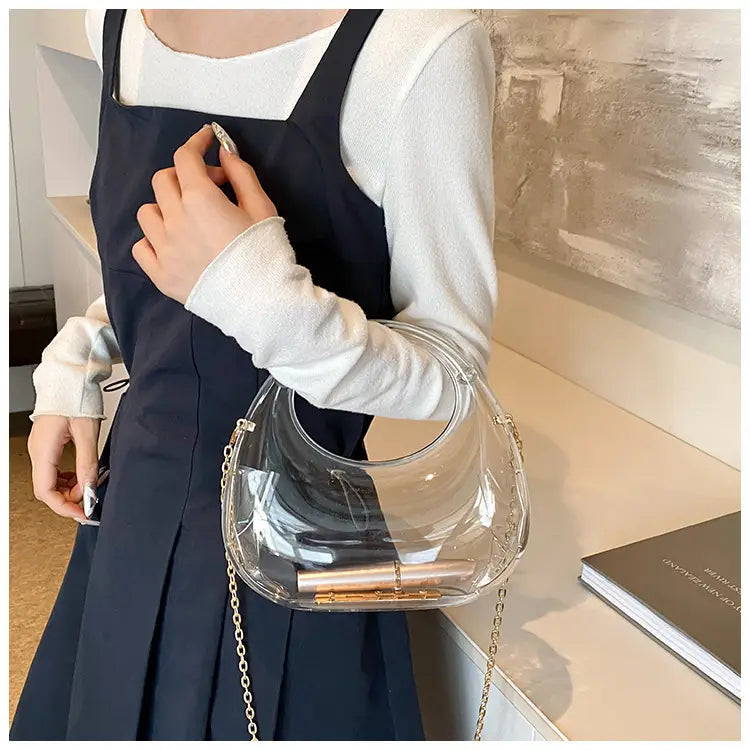 Transparent acrylic handbag featuring a curved handle and a gold-tone chain strap designed as an acrylic gold chain handbag metallic clutch bag.