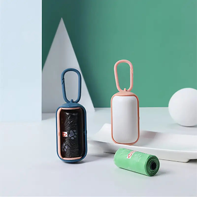Pet poop bag dispenser with carabiner clip in blue and pink for convenient pet waste disposal.