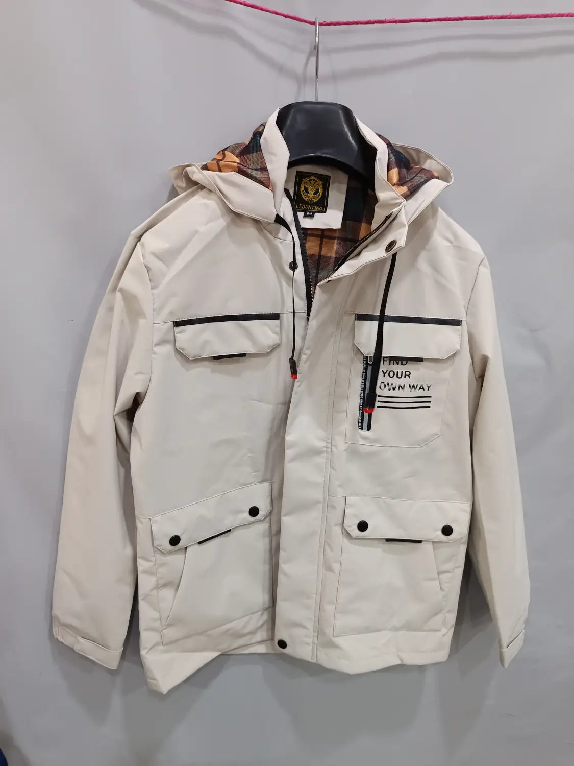 Men winter hooded parka coat in cream color with black trim, plaid lining, front pockets, and find your own way text.
