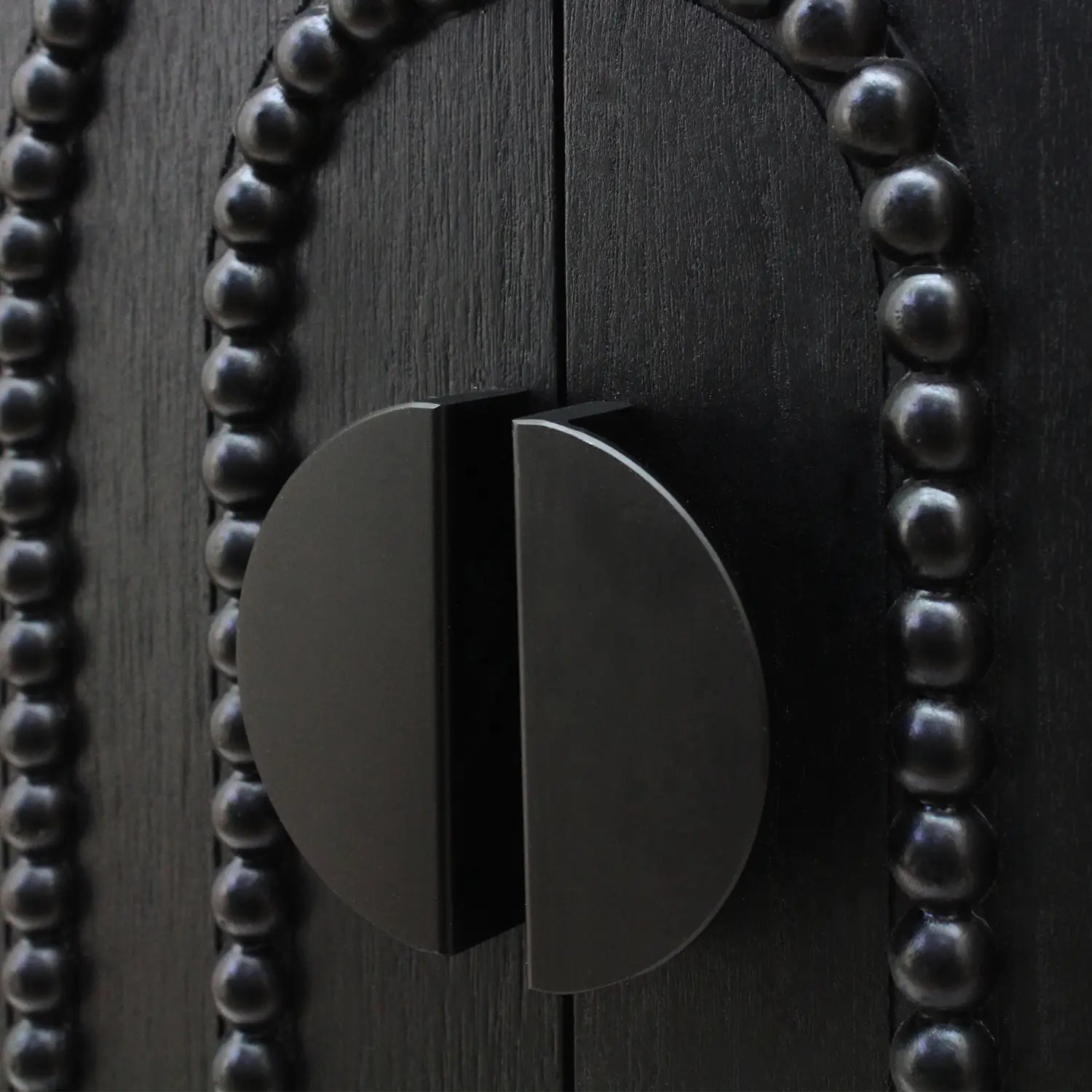 black matte finished circular cabinet handle with a sleek modern design on a black storage cabinet with arched beaded door 30in sideboard
