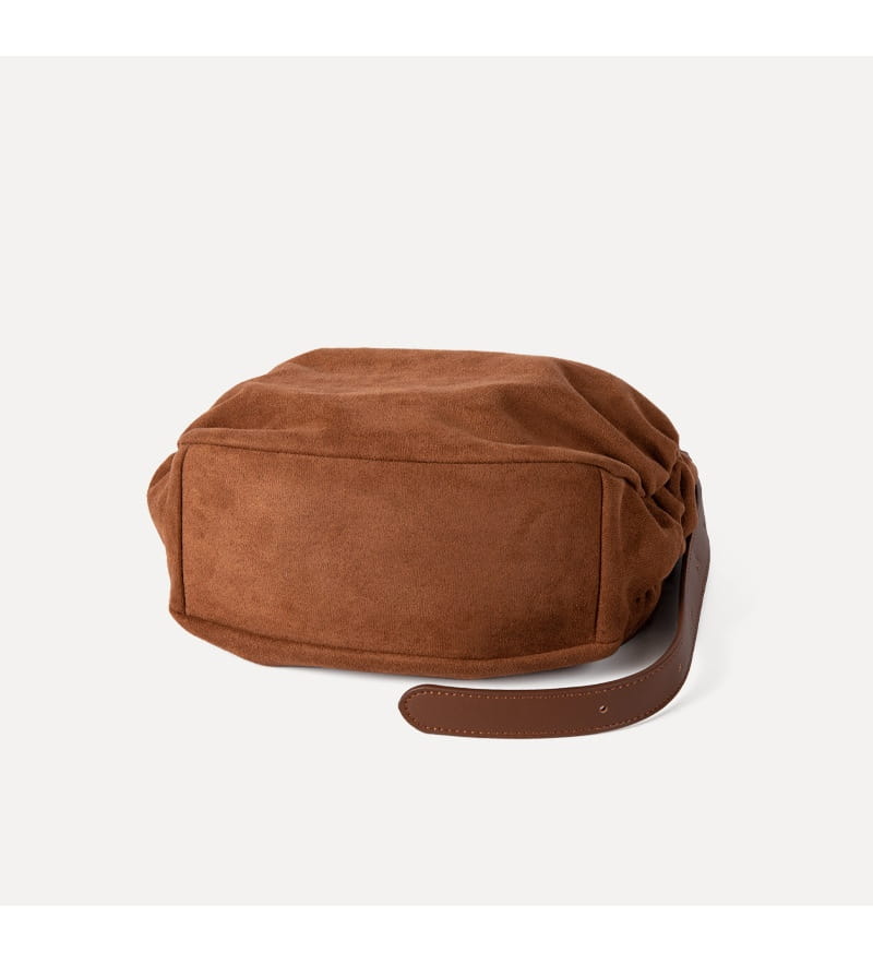 A soft brown suede dumpling shoulder bag with a slouchy drawstring design and matching leather strap for crossbody or hobo use.