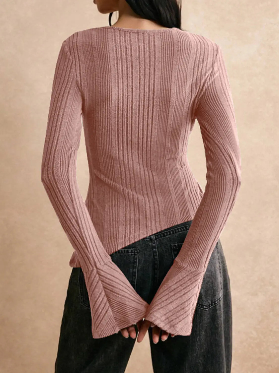 A soft pink ribbed knit long-sleeve cutout top with a flared asymmetrical hemline.