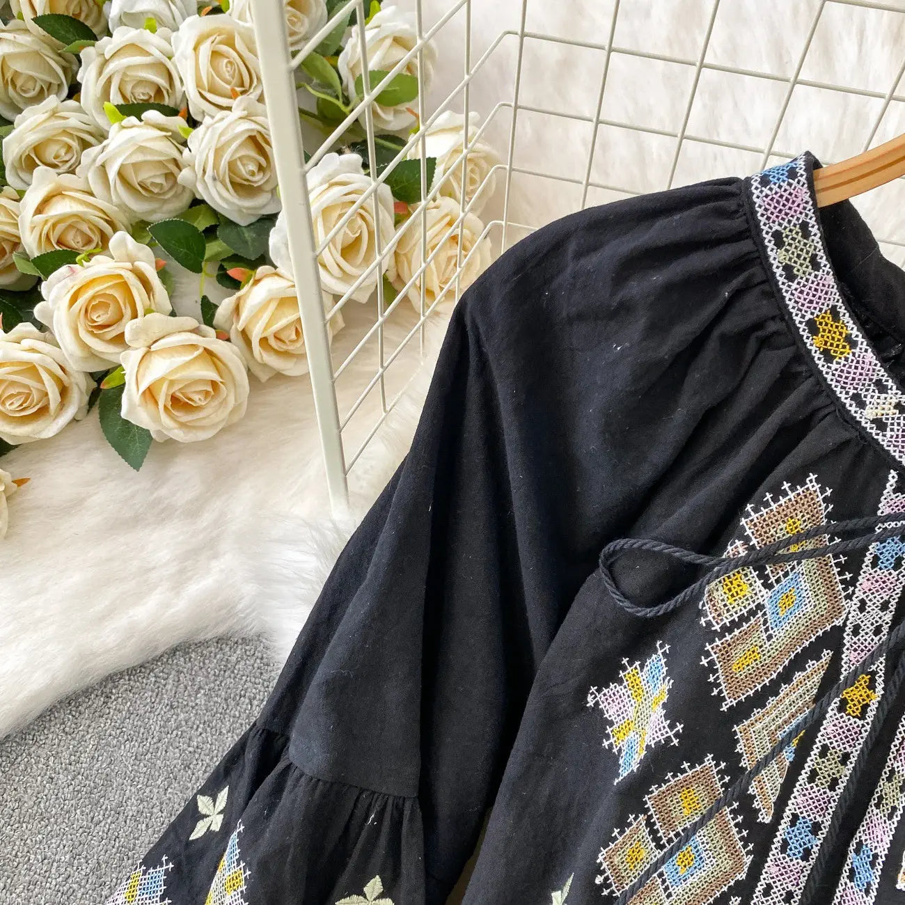 Black embroidered lantern sleeve tie neck blouse featuring colorful yellow blue and white geometric patterns.