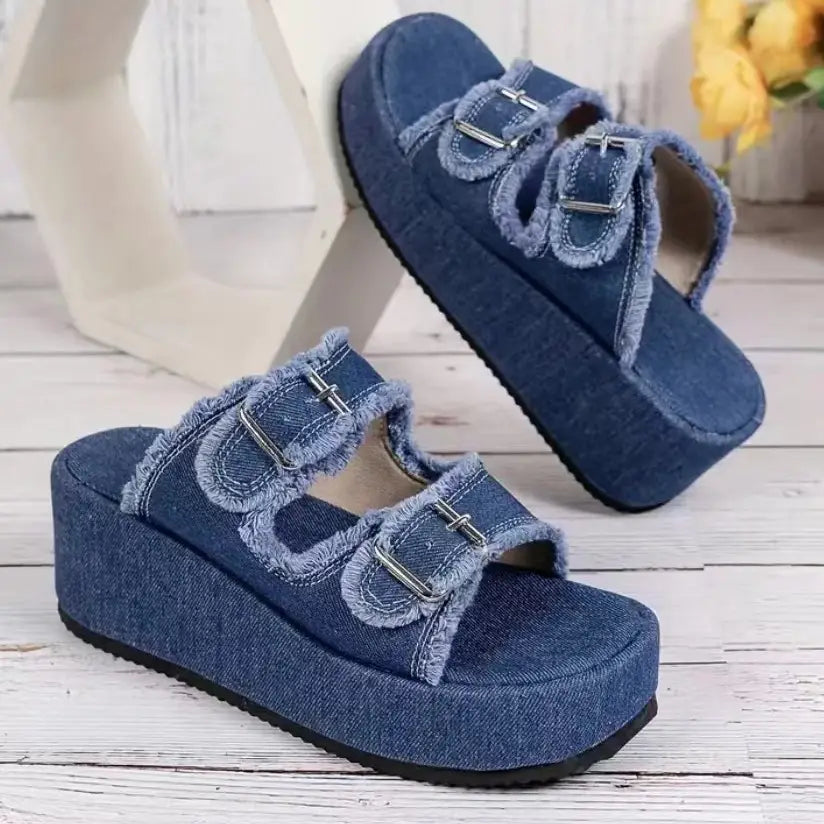 Sandalias de cuña de denim azul con bordes deshilachados y tiras de hebilla plateadas, con diseño de plataforma.