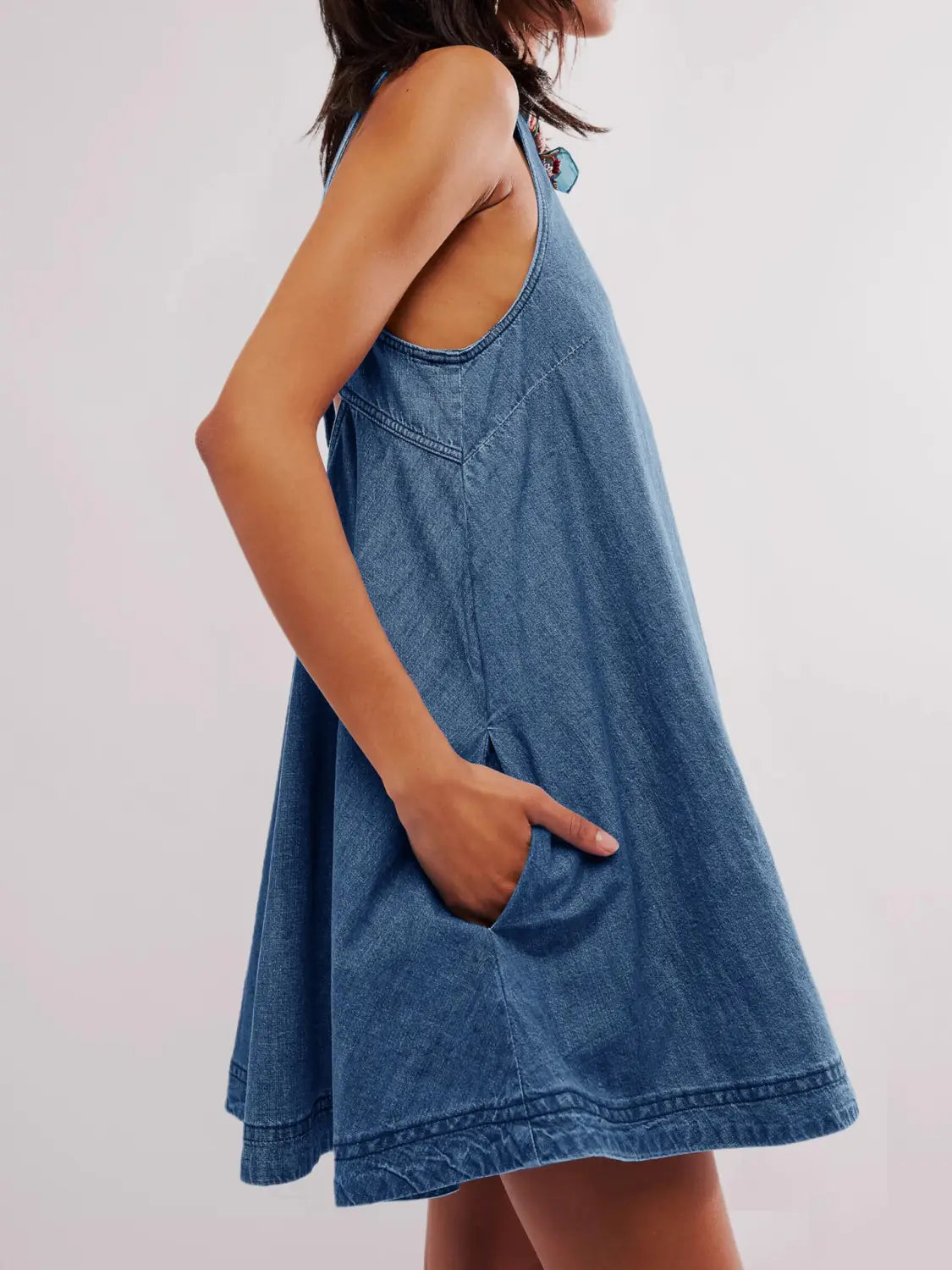 Rückansicht eines Jeans-Minikleids mit hinten offenem Schleifen-Detail, entspannter Passform und schmalen Trägern.