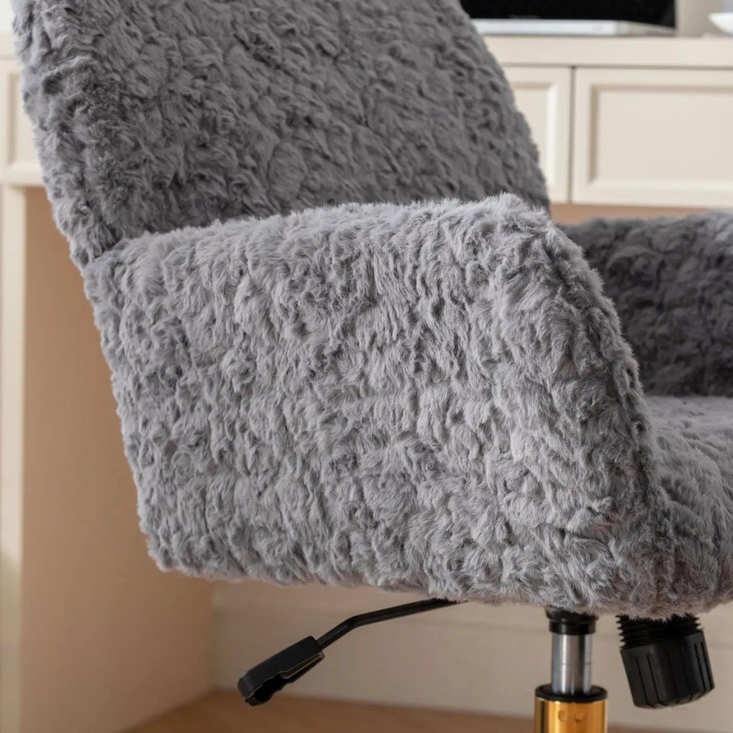 Chaise de bureau en fausse fourrure gris clair, avec une base en métal doré comportant une housse à surface texturée et moelleuse.