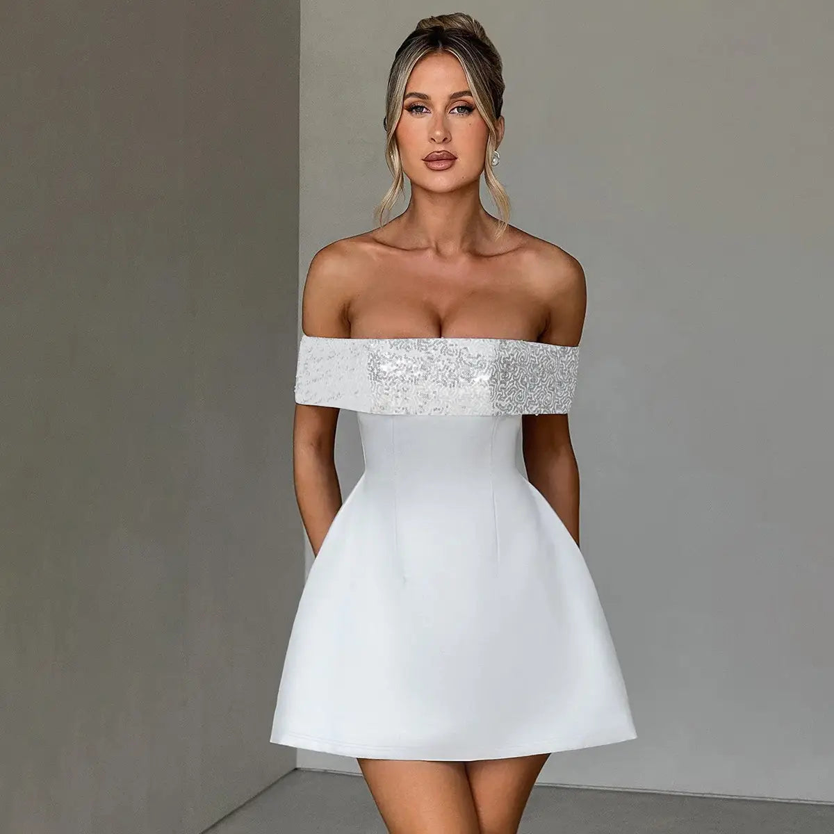White off-the-shoulder bodycon mini dress featuring a sequined bodice and a flared skirt made from elegant material.