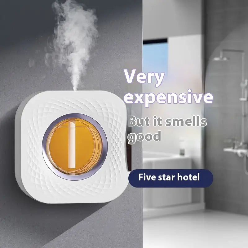 White square-shaped wall-mounted aroma diffuser with a textured surface and an amber-colored central panel designed as a smart rechargeable dispenser.