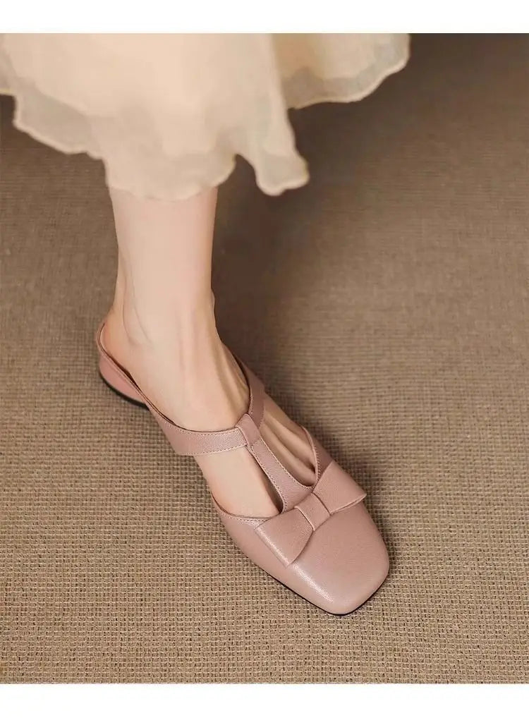 Beige leather square-toe closed toe mule flats for women featuring a bow detail on the vamp.