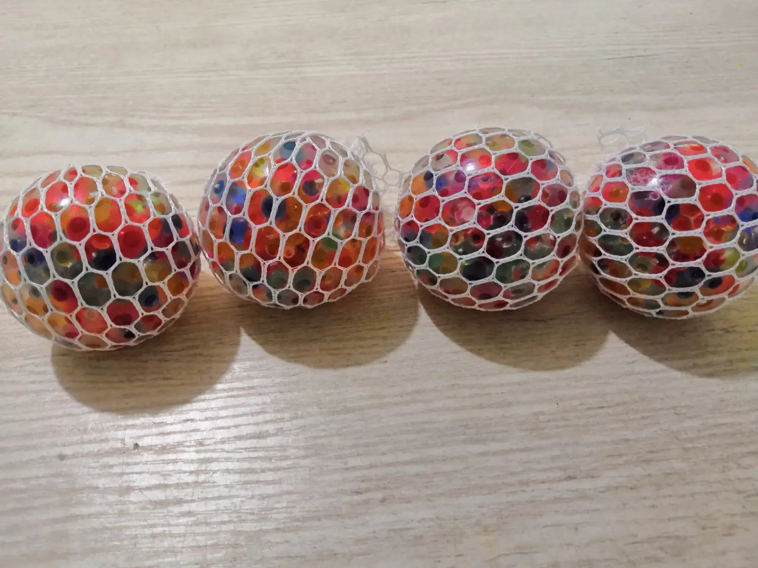 four colorful translucent led mesh stress balls encased in white netting designed as glowing grape squeeze toys for stress relief.