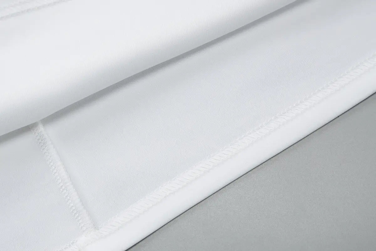 white cotton sheet with neat precise stitching along the edges featured in a sequined off-the-shoulder white bodycon mini dress