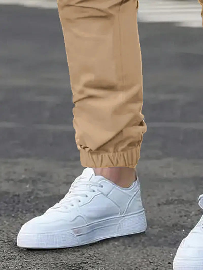 White low-top sneaker with a clean minimalist design and textured rubber sole paired with men’s slim fit cropped cargo joggers with drawstring waist.