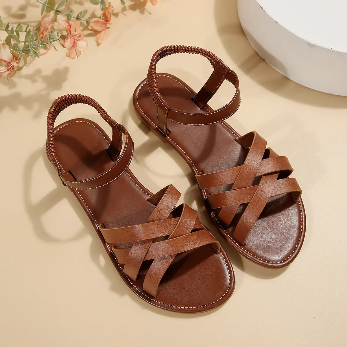 Sandalias de cuero de punta redonda y suela plana color marrón para mujeres, con correas de tobillo trenzadas y correas en la parte delantera entrecruzadas.