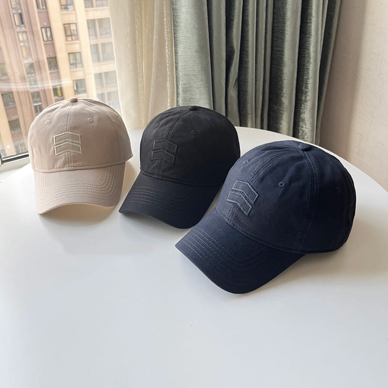 Three men’s large fit cotton baseball caps in beige black and navy blue featuring a minimalist embroidered logo on the front.