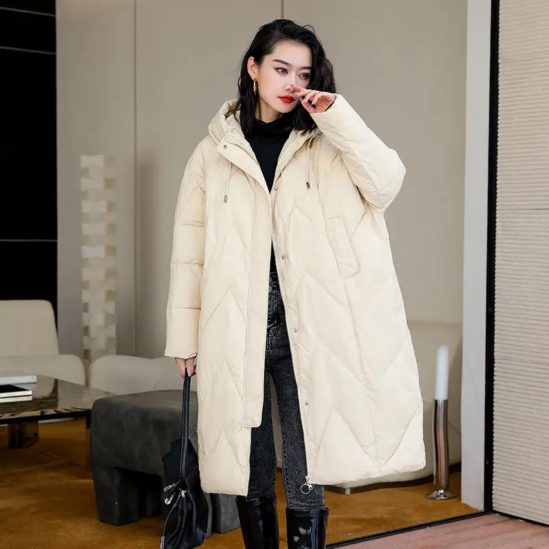 Cream-colored mid length padded down jacket for women with quilted design hood and front zipper suitable for winter wear.