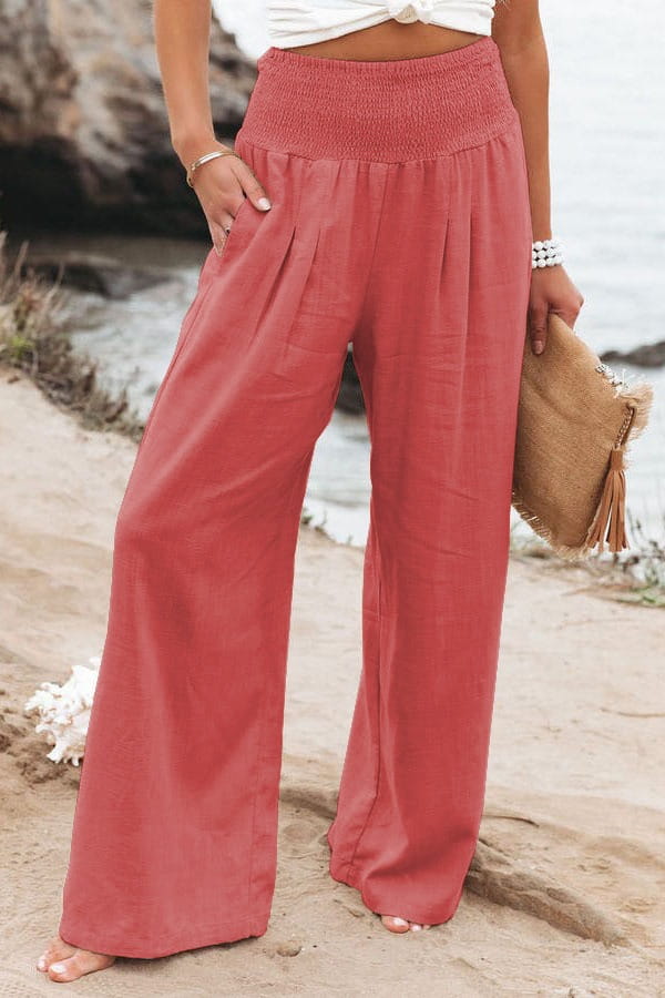 coral-colored smocked wide leg pants for women with a high waist and elastic waistband in solid color design