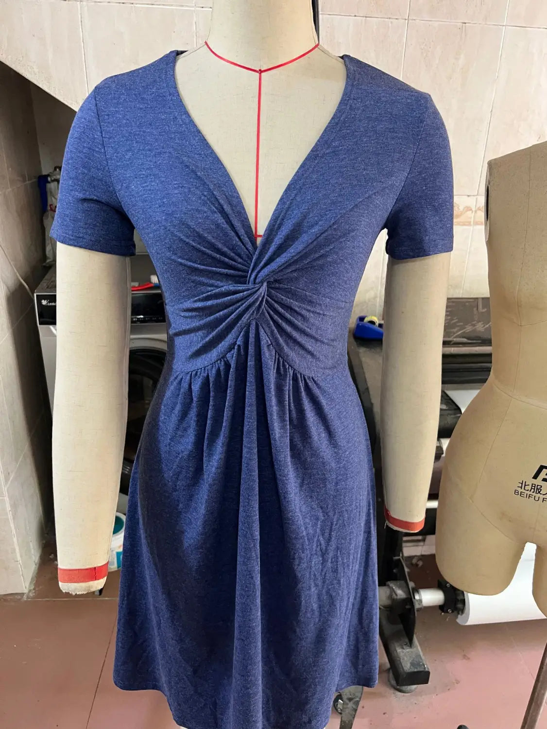 A blue heathered twist front v neck short sleeve midi dress with a gathered front knot detail.