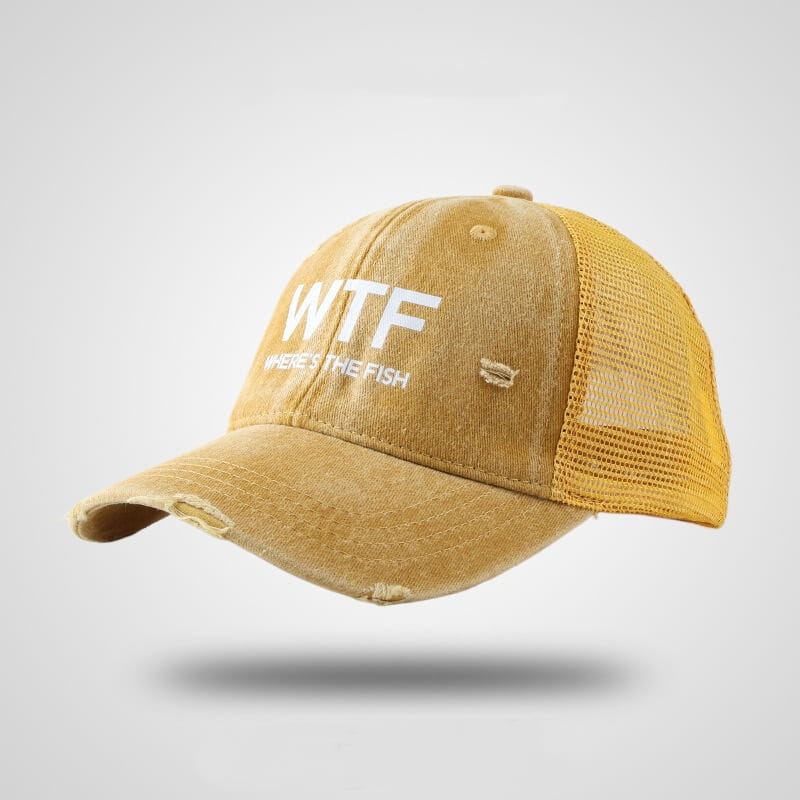A distressed mustard-yellow fishing trucker hat with a mesh back and white embroidered text reading wtf where’s the fish.