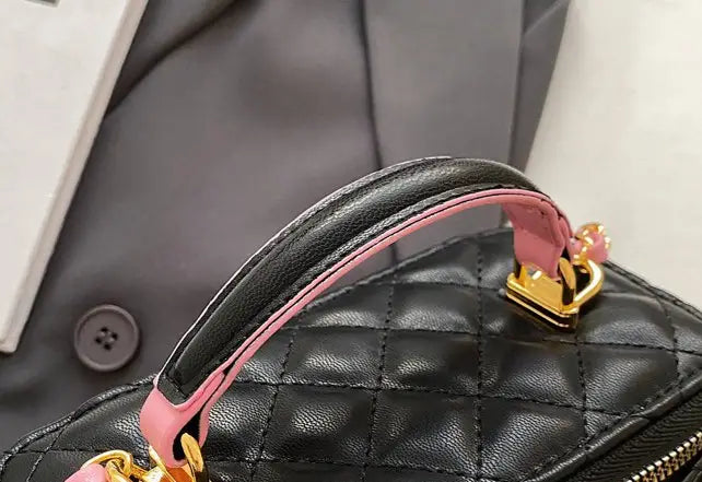 Black quilted diamond chain crossbody bag made of pu leather with pink handle and gold-tone hardware.